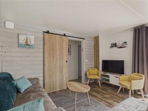 un salon avec un canapé, des chaises et une télévision dans l'établissement Chalet pour 6 - Piscine chauffée - Terrasse, à Bretignolles-sur-Mer