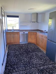 una cucina con mobili in legno e un tappeto nero di Guest house in Röinge Hässleholm a Röinge Altre 5 foto