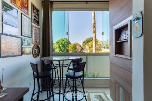 a dining room with a table and chairs in front of a window at Apto 2 Quartos c/ Ar a 270m da Praia GPS0102 in Imbituba