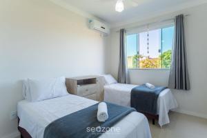 a hotel room with two beds and a window at Apto 2 Quartos c/ Ar a 270m da Praia GPS0102 in Imbituba