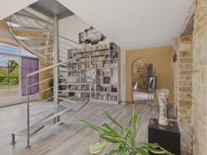 a spiral staircase in a living room with a book shelf at Belle maison pour 6 - Piscine - Dordogne in Saint-Julien-de-Lampon