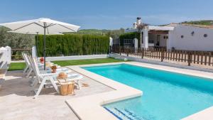 a swimming pool with an umbrella and a table and chairs at Cortijo Casablanca Villanueva de la Concepción by Ruralidays in Villanueva de la Concepción