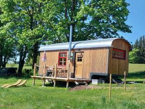 a wooden cabin with a porch in a field at Benno der Wagen - kreativ gestaltetes Tiny House AM WALDRAND Nahezu Alleinlage Rennsteig Grünes Band NATUR PUR Hund willkommen in Tettau