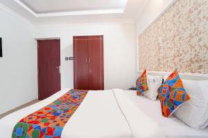 ein Schlafzimmer mit einem großen weißen Bett mit bunten Kissen in der Unterkunft FabHotel Rajathi Holiday Peak in Kodaikanal