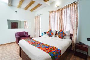 ein Schlafzimmer mit einem großen Bett und einem Stuhl in der Unterkunft FabHotel Rajathi Holiday Peak in Kodaikanal