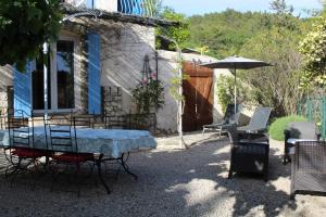 a patio with a table and chairs and an umbrella at la villa des six ifs - Le mûrier in Flayosc