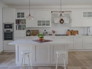 a kitchen with white cabinets and a white island with stools at Casa Pietra Bianca Fay in Castellana Grotte