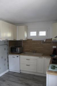 a kitchen with white cabinets and a sink and a microwave at la villa des six ifs - Le mûrier in Flayosc +6 photos