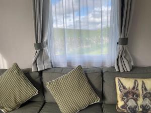 a couch with two pillows in front of a window at One Muirfield, Caravan at Turnberry in Turnberry