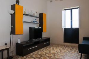 a living room with a tv and a black door at House next to sea, grand & unique Maltese style in St Paul's Bay