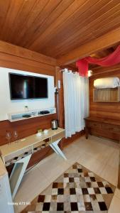 a room with a desk with a tv on the wall at Pousada Requinte Serrano in Urubici