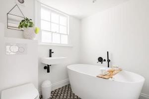 a white bathroom with a tub and a sink at Central Georgian Townhouse with Free Parking in Bath
