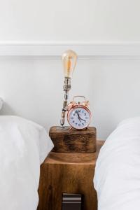 an alarm clock on a wooden table next to a bed at Central Georgian Townhouse with Free Parking in Bath