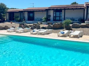 una piscina con sedie a sdraio e una casa di Agriturismo Nuraghe Tuttusoni a Aglientu