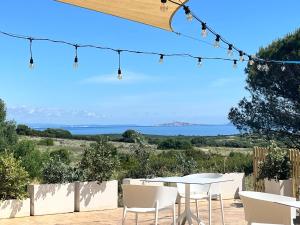 un tavolo e sedie con vista sull'oceano di Agriturismo Nuraghe Tuttusoni a Aglientu Altre 37 foto