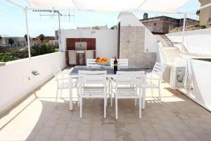 a balcony with a table and chairs on a roof at Favignana Margothouse white blue arancio in Favignana