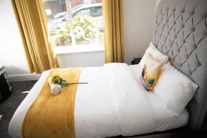 ein weißes Bett mit Blumen darauf vor einem Fenster in der Unterkunft Kyoto Central I 4 BDR House I 50 inch Smart TVs in Rooms I Large Spacious Rooms I Refurbished I Derby City Centre in Derby