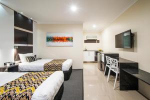a hotel room with two beds and a kitchen at Abbey Motor Inn in Grafton