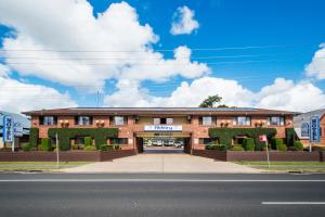 a large brick building with plants on the front at Abbey Motor Inn in Grafton