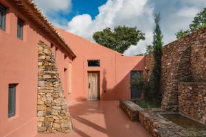 ein orangefarbenes Gebäude mit einer Steinmauer und einer Tür in der Unterkunft Vale Palheiro Earth Resort - Soft Opening in Aljezur