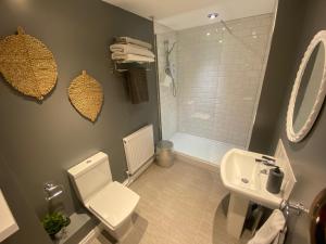 a bathroom with a toilet and a sink and a shower at Sanctuary Rooms in Brightlingsea +13 photos