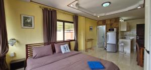 a bedroom with a bed with purple sheets and a kitchen at Rawai Condotel 3 in Rawai Beach