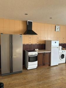 a kitchen with a refrigerator and a washer and dryer at Kaņiermāja in Lapmežciems