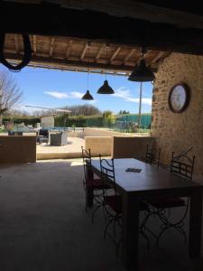 un tavolo con sedie e un orologio su un muro di pietra di Mas del sol a Cahuzac-sur-Vère
