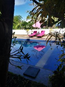 una piscina con sedie e ombrelloni rosa di La Pernela Resort a Dauis