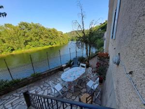 balkon ze stołem i krzesłami przy rzece w obiekcie Les reflets du tarn w mieście Ambialet