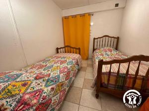 a bedroom with two beds and a yellow curtain at La villa blanche - 4 personnes in Saint-Jean-de-Fos +7 photos