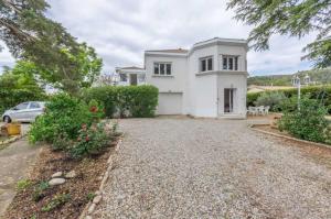 a white house with a car parked in the driveway at La villa blanche - 4 personnes in Saint-Jean-de-Fos