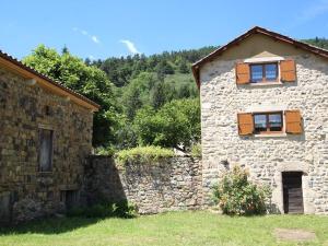 una casa in pietra con due finestre e un muro di pietra di Gîte pittoresque en bord de rivière avec jardin clos, proche sports et sites touristiques - FR-1-582-176 ad Alleyras