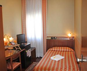 ノヴェンタ・ディ・ピアーヴェにあるAlbergo Ristorante Leon d'Oroのベッド、デスク、テレビが備わるホテルルームです。