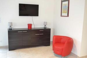 a red chair sitting in a room with a tv at Collioure in Latour-Bas-Elne