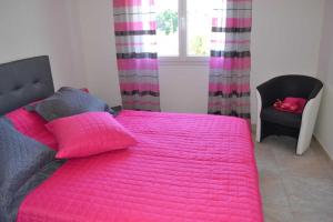 a bedroom with a pink bed with a chair and a window at Collioure in Latour-Bas-Elne