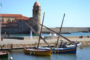 a boat sitting in the water next to a clock tower at Collioure in Latour-Bas-Elne