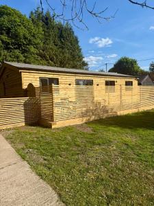 a wooden building with a fence in a yard at Southend Long Barn in Ogbourne Saint George +11 photos