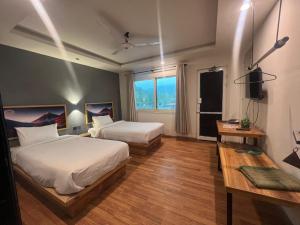 锡卡都Eat and Read Hotel的一间卧室，有两张床、一张桌子和一扇窗户 更多9张照片