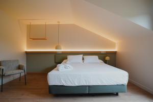 a bedroom with a white bed and a chair at Hotel Los Pasiegos in Hoznayo