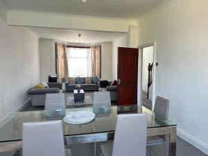 a living room with a glass table and white chairs at Spacious Family Friendly 4-Bed Holiday Home in Ilford +25 photos