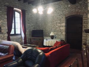 a living room with a couch and a stone wall at Ancienne ecole de moncere in Penne