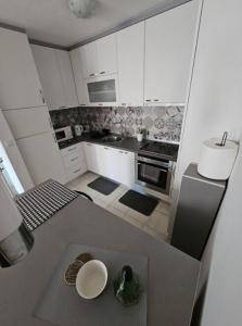 une petite cuisine avec des armoires blanches et un évier dans l'établissement Lovely 1-bedroom rental unit with free parking, à Sarajevo 21 autres photos