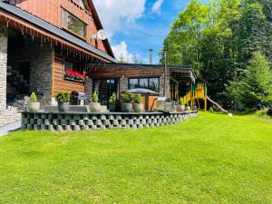 una casa con césped delante en Rioba Chalet, en Nová Bystrica