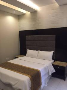 1 dormitorio con 1 cama grande y cabecero negro en Rukon Buotat 15, en Riad