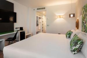 a hotel room with a white bed and a desk at Catalonia Málaga in Málaga