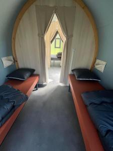 two beds in a small room with an arched doorway at Camping le Convivial CocoSweet 4 personnes in Saint-Martial-de-Nabirat