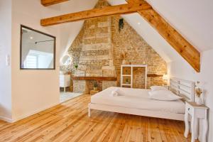 a bedroom with a white bed in front of a brick wall at La suite Nacrée - Magnifique Studio in Bernières-sur-Mer
