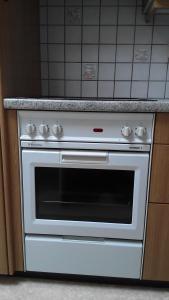 La cocina está equipada con fogones blancos. en Neumühleweg 19 en Lauperswil