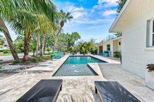 a swimming pool with two benches next to a house at Beach Walk Cottage - 451 in Siesta Key